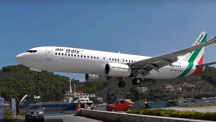 Самолёт пролетает так низко над греческим островом, что почти срезает крышу внедорожнику